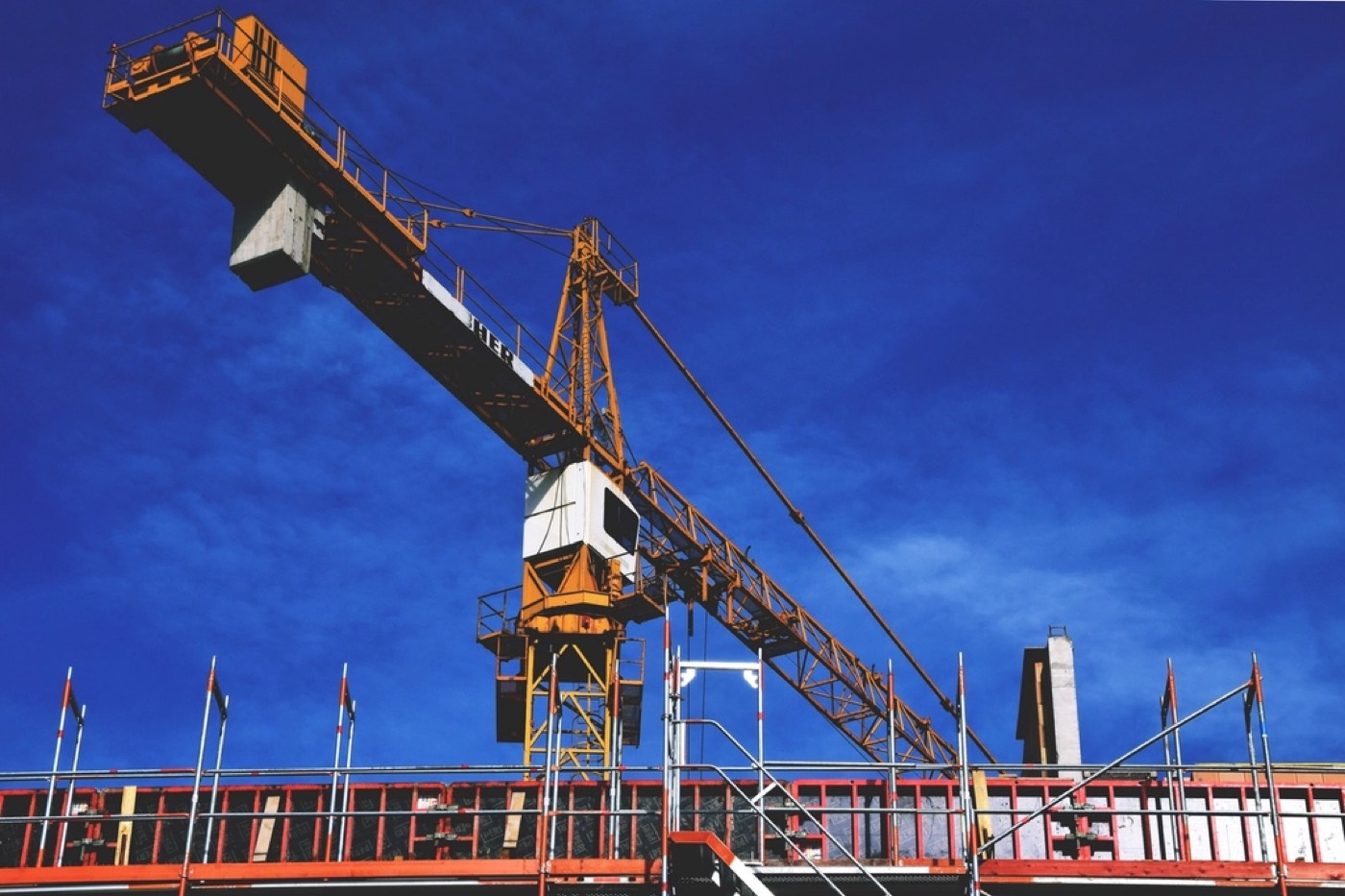 A tower crane over a construction site against a blue sky